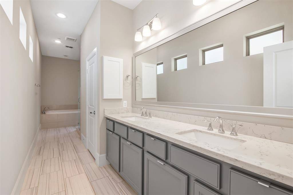 Massive primary bathroom has transom windows, tiled floors, double vanities and loads of storage space.