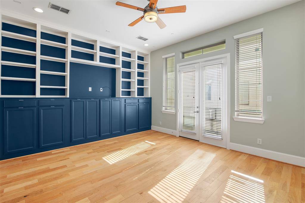 Large family room features a wall of custom built cabinetry and shelves. The door opens to a small patio on the front of the house.