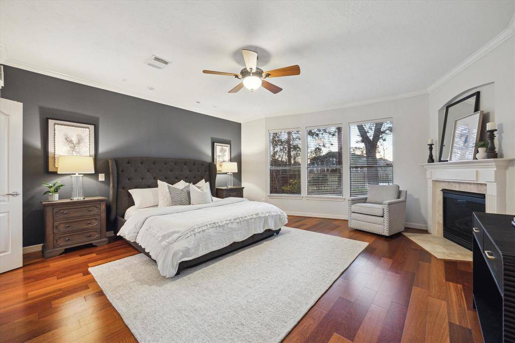 The expansive primary suite offers serene lake views, creating a tranquil retreat. With plenty of space to unwind, it features an elegant accent wall and rich wood floors further enhance the room's warmth and charm.
