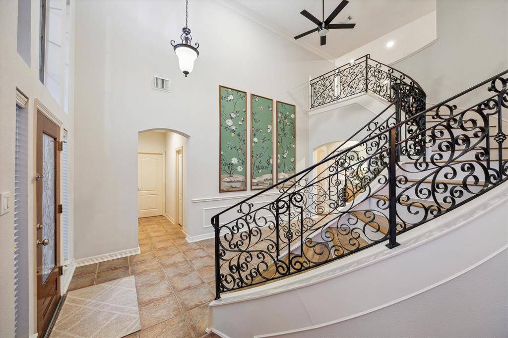 The entry features an elegant curved staircase highlighted by a beautifully designed iron banister and railing. Down the hall straight ahead is the powder room, study, and laundry room leading to the garage.