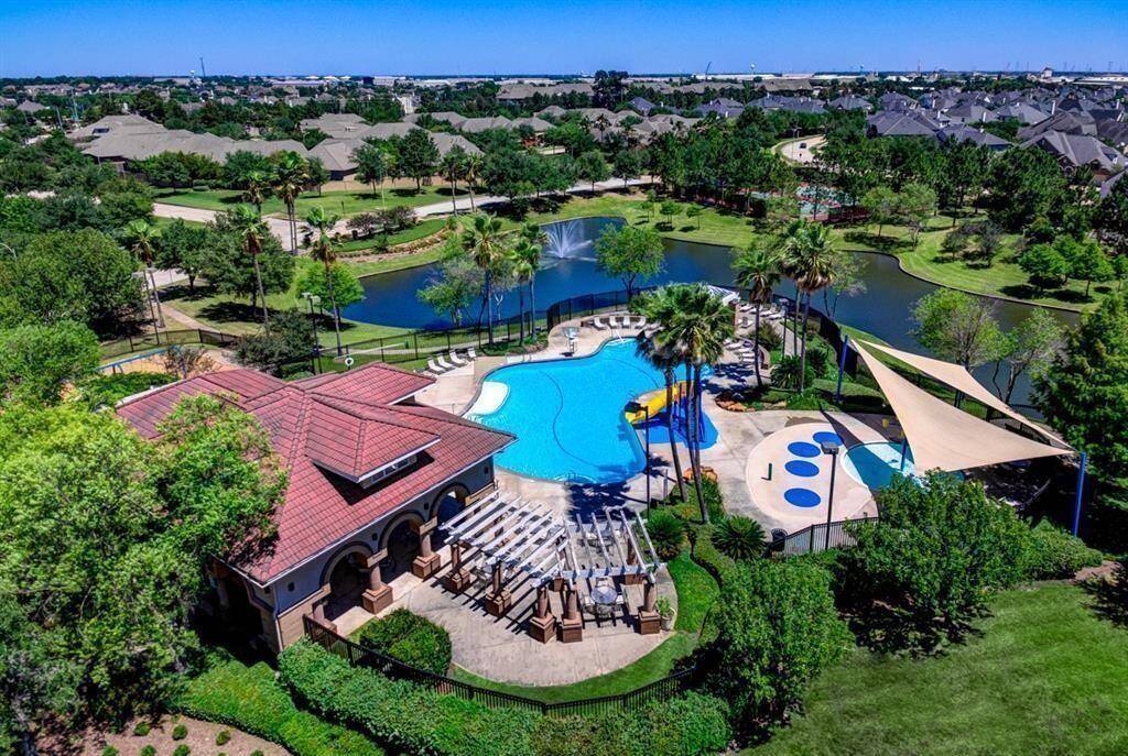 A view of the community pool closest to the home with slide and splash pad. Lakes on Eldridge North is gated and guarded with 24 hour manned gate, multiple lakes, and many amenities, including a clubhouse, fitness center, lighted tennis courts, pickleball, sand volleyball, 2 pools, 2 playgrounds, sidewalks and trails.
