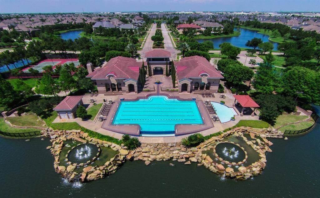 A view of the clubhouse and main pool. There is a fitness center inside the clubhouse. Tennis courts are seen to the left and summer concerts are held lakeside at the gazebo to the right.