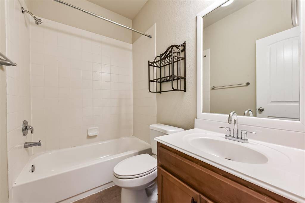 Charming secondary bathroom featuring a tub-shower combo and a stylish vanity with ample storage.