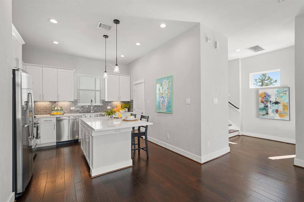 Bright & cheery, the kitchen includes a quartz surfaced island with breakfast bar seating illuminated by pendant lighting.