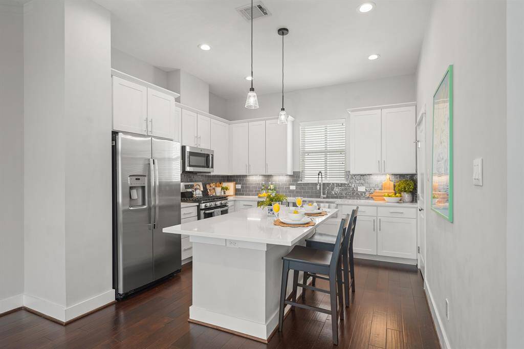 Surrounded by 42" Shaker-style cabinets capped with crown moulding, under-cabinet lighting & soft close cabinets & drawers, this gorgeous kitchen includes quartz counter tops with a subway tiled back splash & hardwood floors.