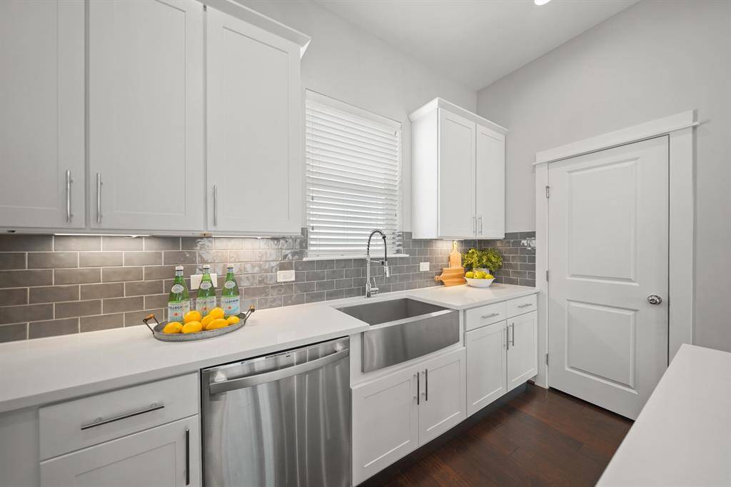 A window with blinds sits just above a stainless steel apron sink accompanied by plenty of counter space on each side.
