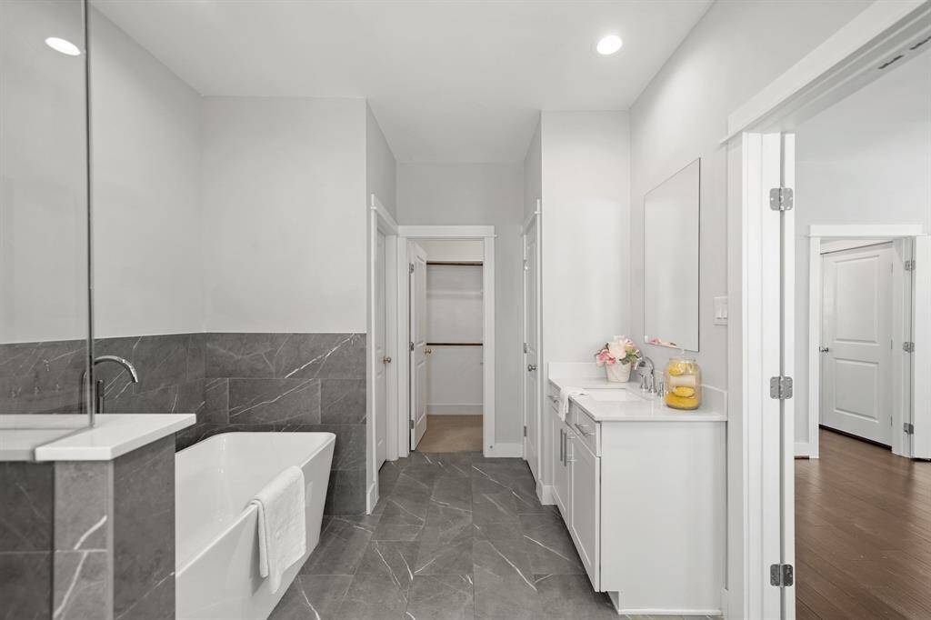 Luxury awaits you in this private bath complete with dual dressing areas with painted Shaker-style cabinets, quartz counter tops and under-mount sinks accompanied by wall mounted mirrors.