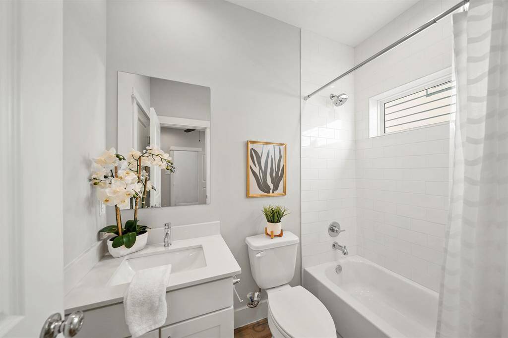 Serving as the home's third full bath, this ensuite bath has painted Shaker-style cabinets with quartz counter top & integrated back splash, wall mounted mirror with recessed lighting above, a subway tile surrounded combination with tub/shower with a fixed glass window above and 12" x 24" tile flooring.