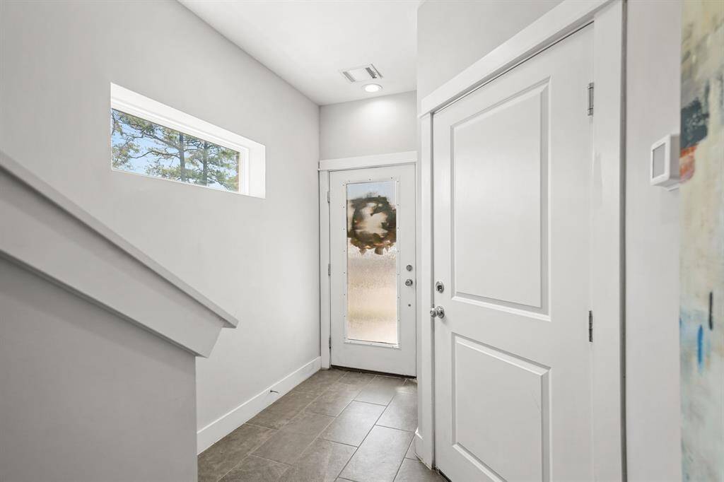Included is a painted front door with privacy rain glass, an upper fixed glass window, under-stair storage closet and access to one of three bedrooms with an ensuite bath. Included is 12" x 24" tile flooring and access to the home's two-car attached garage.