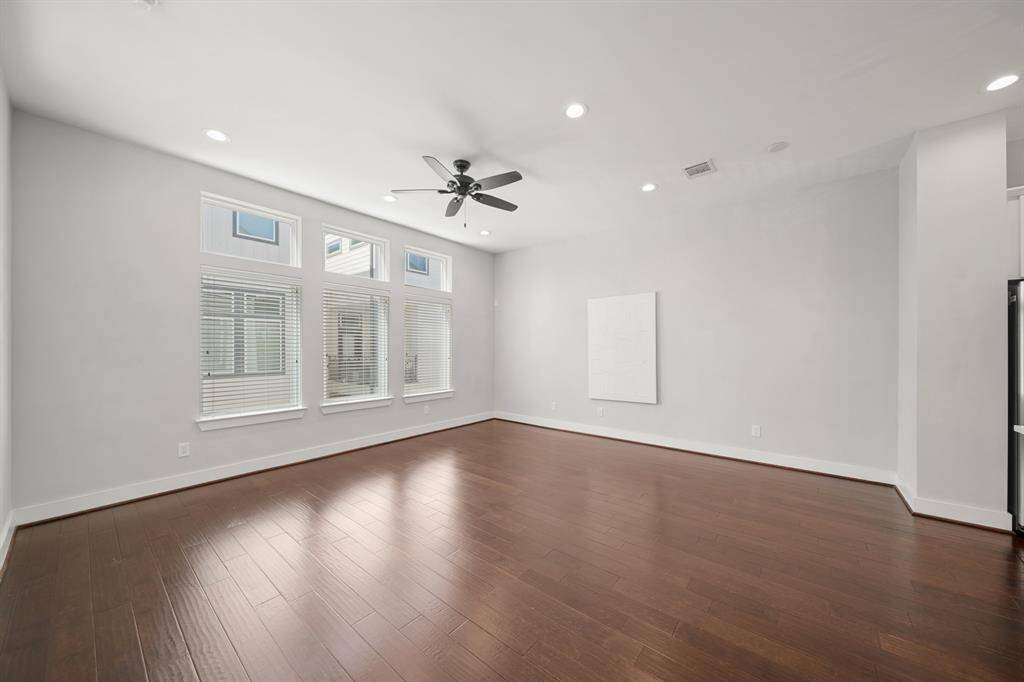 Windows with blinds and transoms overlooking the front of the home fill this living room with plenty of natural lighting.