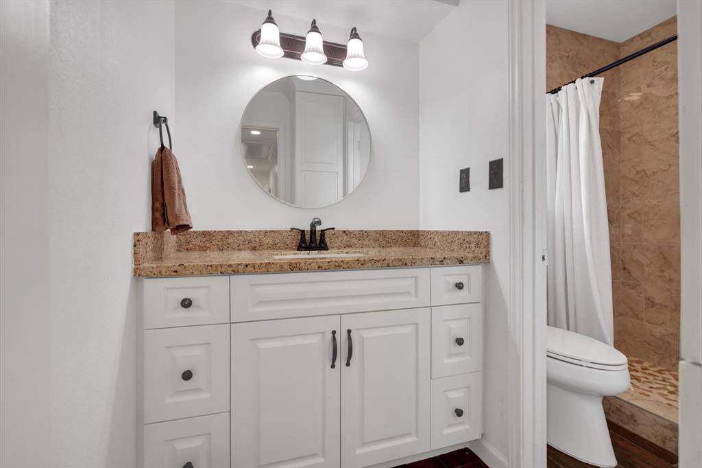 The secondary bath also features custom cabinet with matching granite