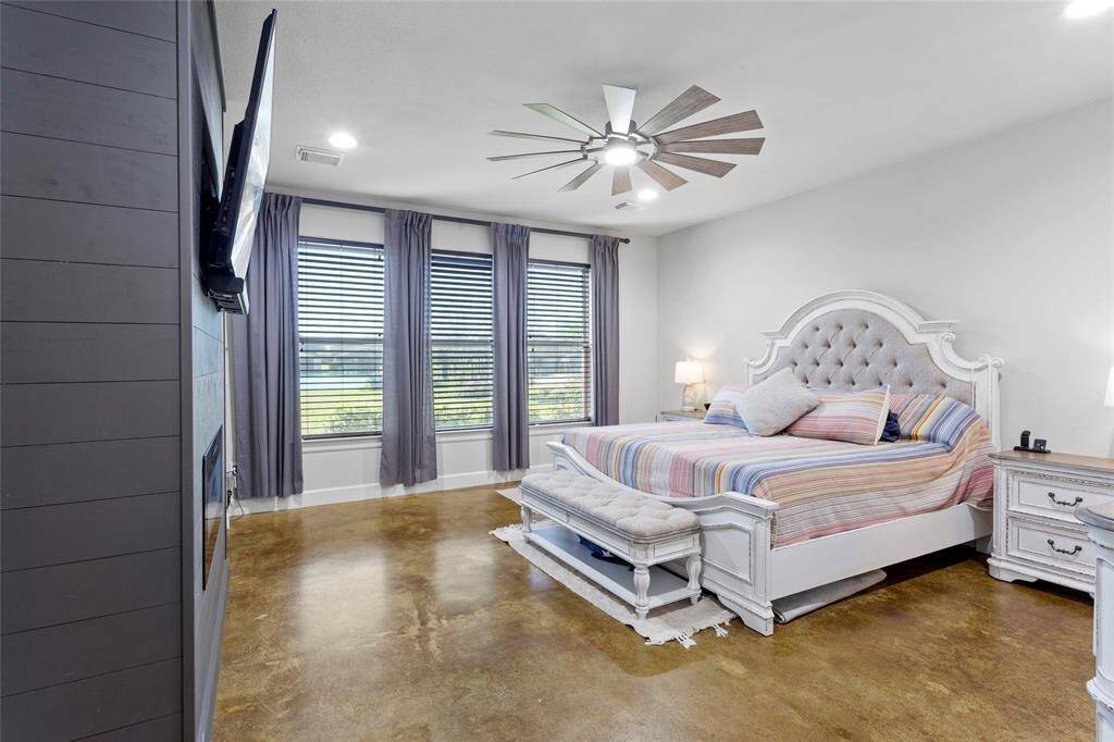 This spacious primary bedroom features an electric fireplace and updated lighting. Natural light pours in through three windows with custom drapery, and lake views from every angle.