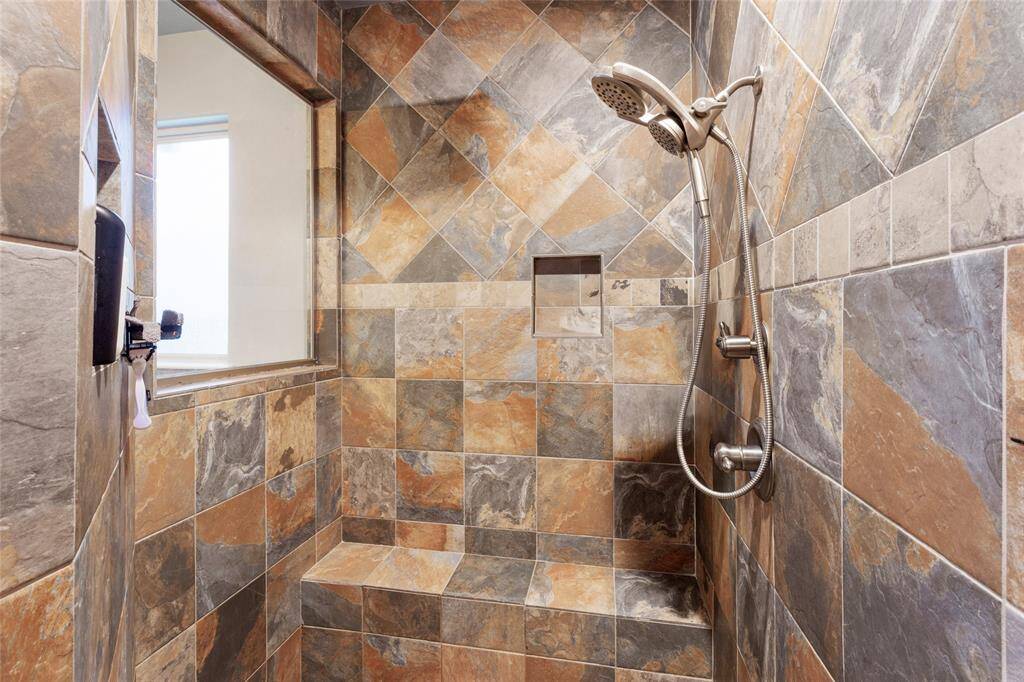 Walk-in shower features a modern showerhead, a built-in bench, and a niche for toiletries, providing both style and functionality.
