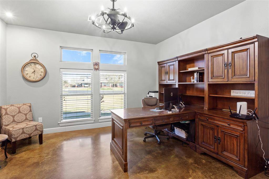 The downstairs home office or flex space has large picture windows, recessed lighting and a modern light/fan fixture.
