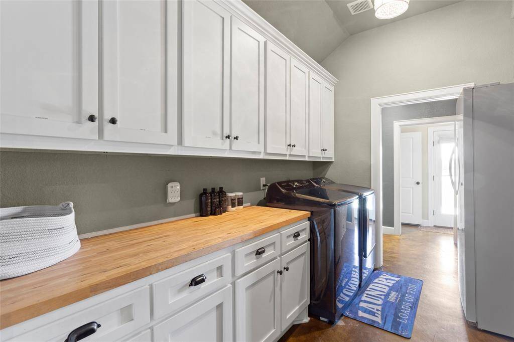 The walk-though laundry room features ample storage space, butcherblock countertops, and electrical for an extra refrigerator or freezer. The space is bright and functional, with a door leading to the guest powder bathroom.