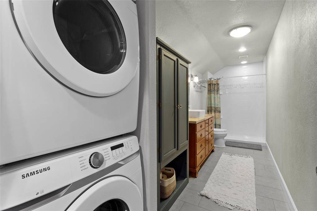 This upstairs bathroom come equipped with stackable washer and dryer! The vintage dresser that was converted into under sink cabinets gives it that truly custom feel.