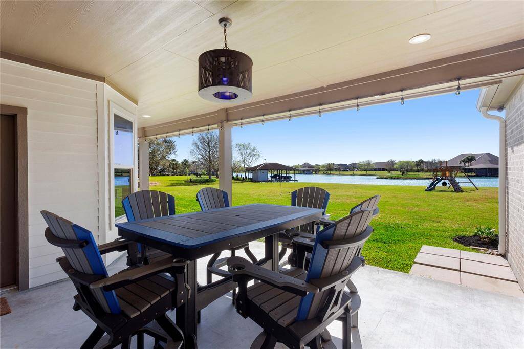 Walk outside and enjoy this covered patio overlooking a massive backyard and a serene lake view, providing a perfect setting for outdoor relaxation and entertaining.