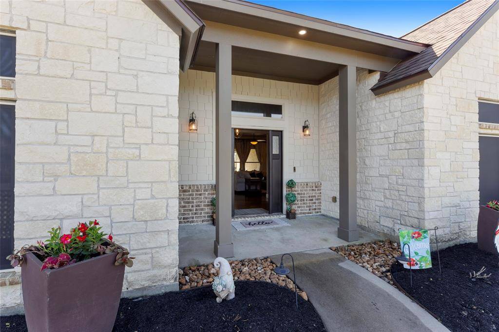 Warm and welcoming front entrance with a covered porch featuring custom stonework and columns.