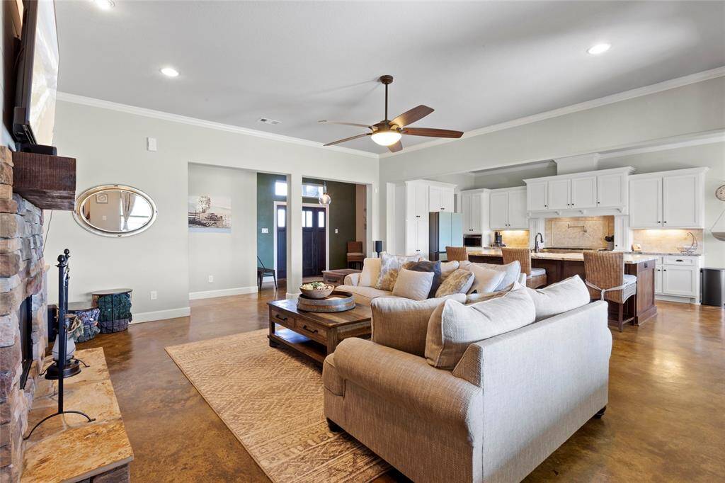 Spacious, open-concept living room with custom stone fireplace and driftwood mantel. The living room is open to the kitchen and dining room, perfect for entertaining.