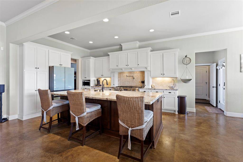 The gourmet kitchen has a spacious layout with an oversized granite island, white solid wood cabinetry, and modern appliances.  There are extra storage cabinets under the island for all the extras.