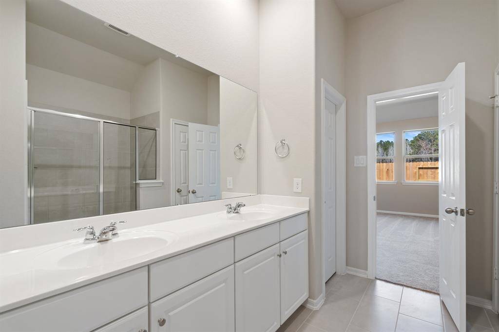 The en-suite bathroom offers a spa-like atmosphere with its elegant design, high end finishes, and tasteful lighting, creating a retreat within your own home.