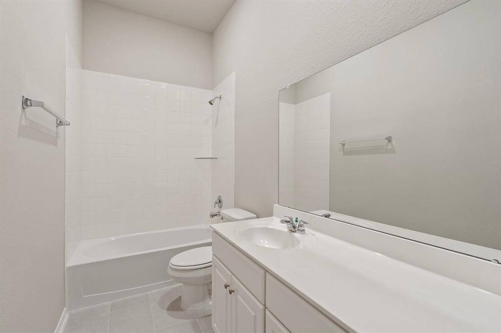 The secondary bath features tile flooring, white cabinetry and light countertops and a shower/tub combo. Perfect for accommodating any visiting family and friends.