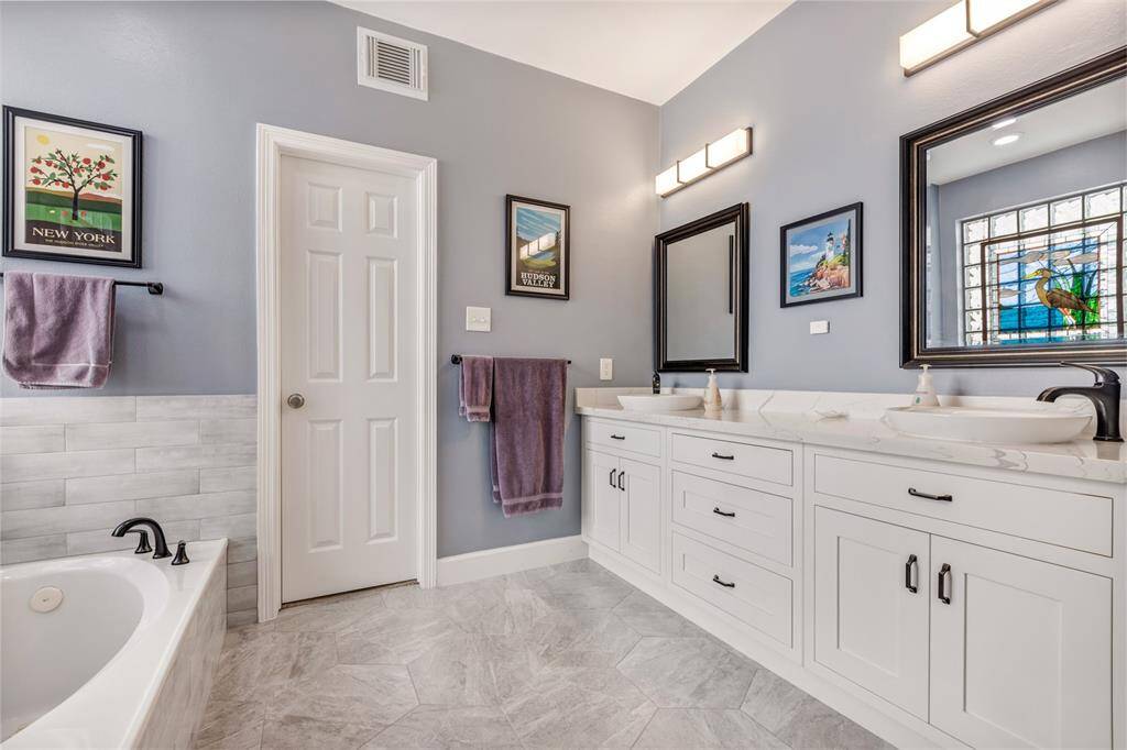 This ensuite bathroom has been renovated with designer touches. This large double vanity made by a local master craftsman and has lots of storage for all your bathroom needs. This updated bathroom has new tilework, lighting, and mirrors.  A separate shower and jetted tub make it an easy place to relax or to get ready to start your day. Beyond the closed door is a large walk in closet that has lots of storage for clothes.