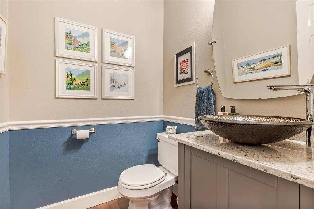 Next to the first home office there's a pretty powder bath. With an updated toilet, vanity, mirror, and a circular vessel sink.