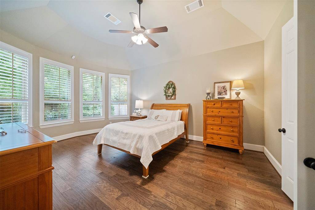 Primary suite features plank flooring, plantation shutters and a wall of beautiful windows.