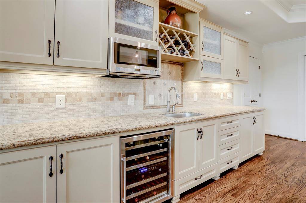 Across from the island is a wet bar area with a second sink, beverage fridge, and more storage options.