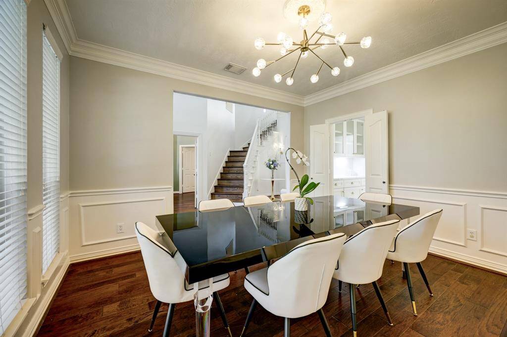 Another view of the formal dining room with wainscotting and crown molding, upgraded modering lighting and entry to the renovated kitchen.