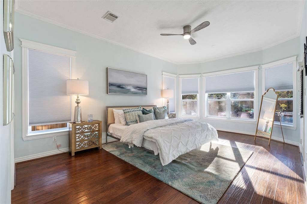 First floor master bedroom with modern new ceiling fans, a wall of windows overlooking the pool, room for a sitting area, and an exterior door to the pool and patio.