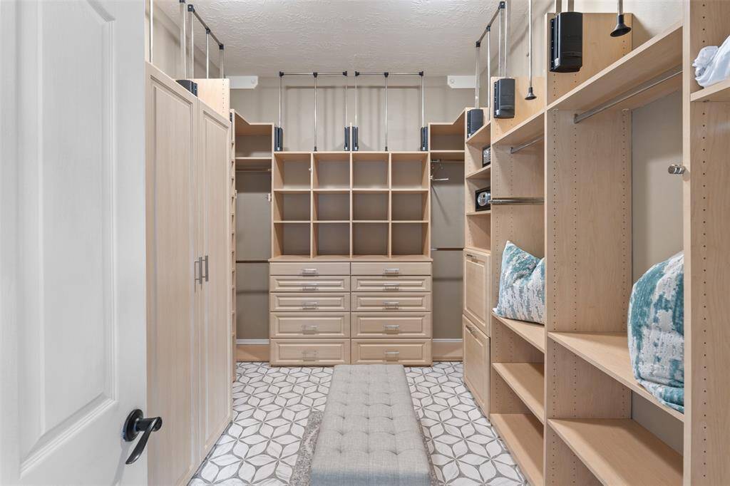 Custom-built master closet has hanging space, shoe shelving, pull down poles for hanging seasonal items, built-ins for all of your clothing displayed in a boutique-style.