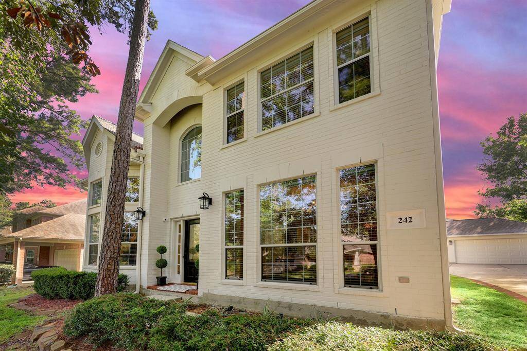This home features a charming exterior with large windows and a welcoming front entrance. The light-colored brick façade is complemented by lush greenery and a well-maintained landscape, creating an inviting curb appeal.