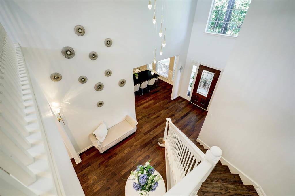 This inviting foyer features high ceilings and abundant natural light, with elegant wooden flooring. The space is beautifully complemented by a graceful staircase and a welcoming front door with side windows.  All of the lighting including the crystal scones, chandeliers have been upgraded throughout the home.