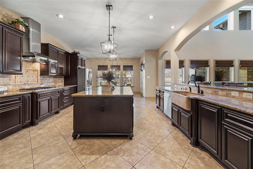 The sprawling center island serves as a versatile centerpiece, providing additional workspace and storage. Lit with beautiful pendant lighting highlighting the beauty of the countertops.