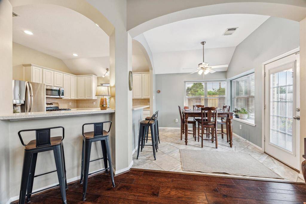 Seated bar area overlooking the large kitchen with the breakfast room, surrounded by windows, to the back right.