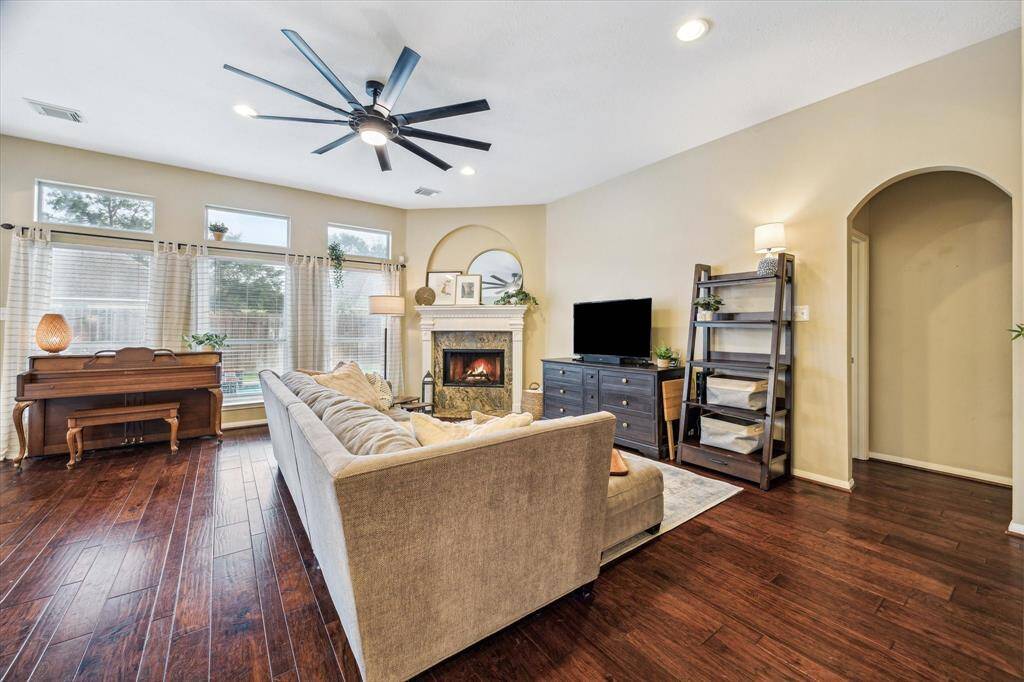 Beautiful engineered wood floors in this large living space with a cozy fireplace.  Through the arched entryway on the right is the very nice 1st floor primary bedroom,