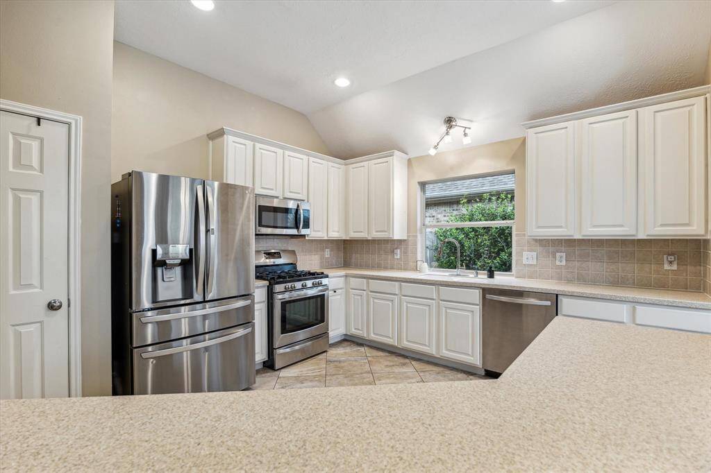 A spacious kitchen with a window and stainless appliances.  This kitchen has an abundance of pretty white cabinets and has room for all to move around freely.  It overlooks the living area and breakfast room.