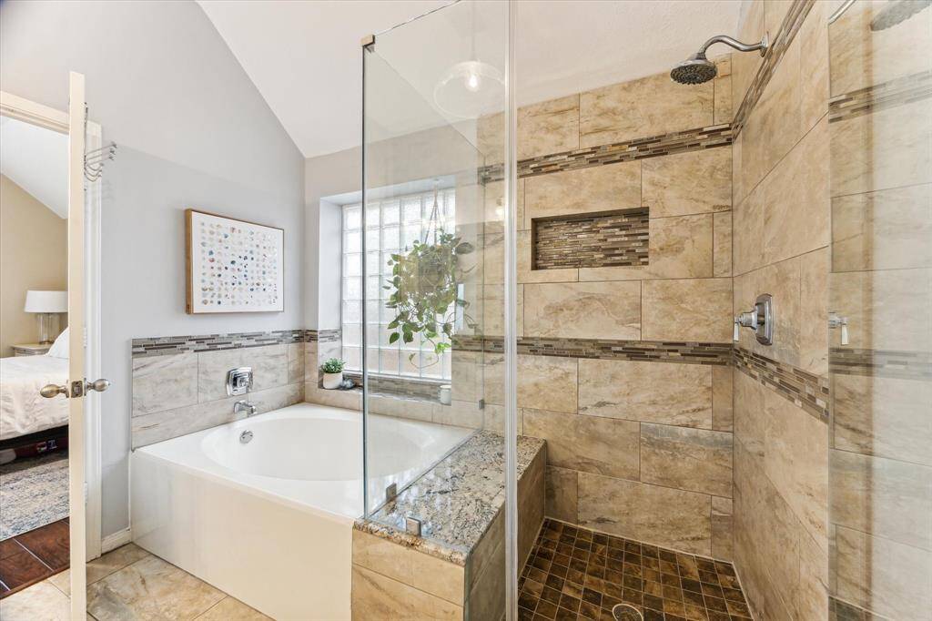 Another view of the updated bath with seamless shower with built in seat and a nice soaking tub with glass block window.