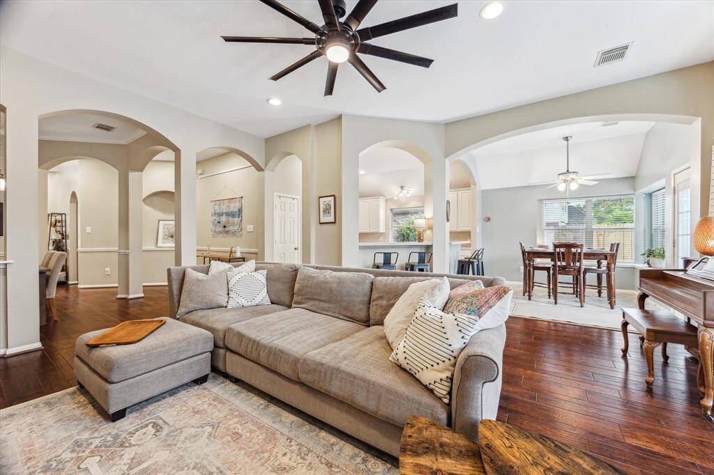 Another view of the living area viewed from the surrounding fireplace area. You can see the breakfast room, the kitchen and the dining room all from this area. Note the beautiful arched entryways to each room. This room backs to the primary bedroom located in the back of the home.