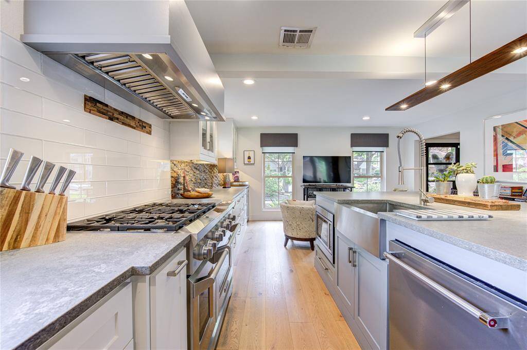 Close up view of these amazing countertops with glass subway tile backsplash and wood accents. The stainless farmhouse sink blends perfectly with the high end Kitchen Aid appliances.