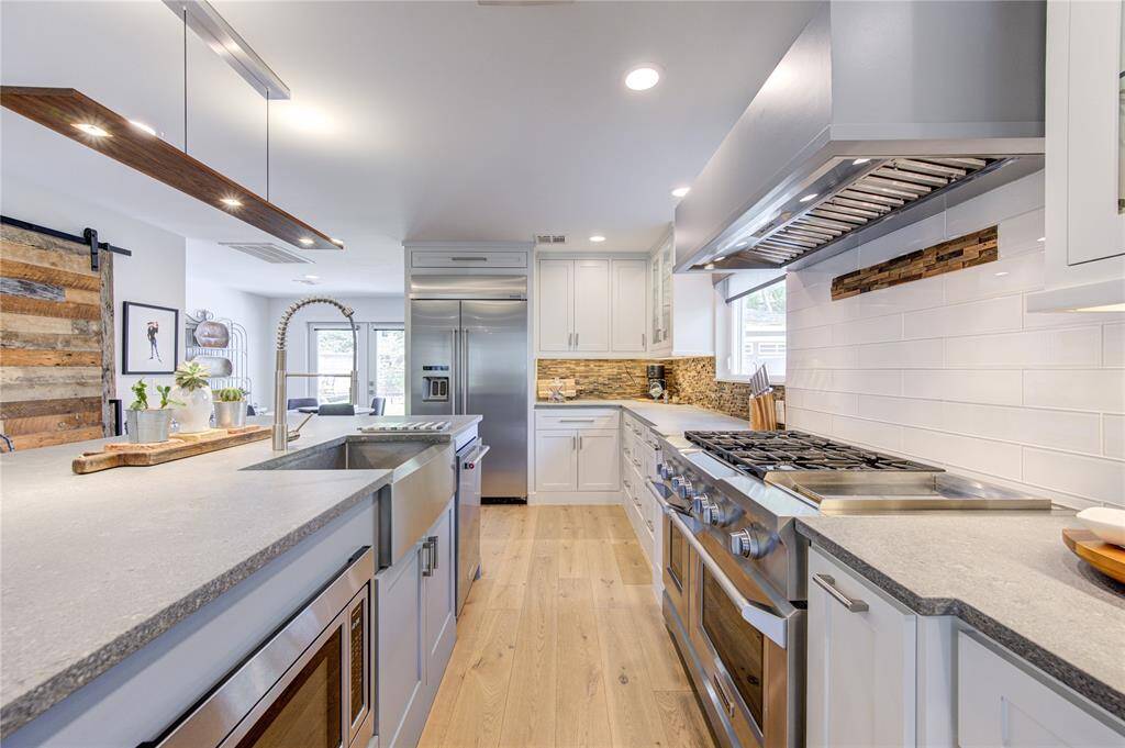 This modern design of this island kitchen blends some of the HOTTEST TRENDS in kitchens with sleek Concrete look counters with natural wood accents in the backsplash. Check out the cool island light with wood and LED lighting! The Professional Series 6-burner gas range will be a delight to cook on.