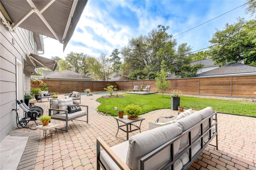This home has it all-- a large back yard with green space, a pool, and lots of outdoor entertaining space. Both awnings extend to extend the shaded area over the patios.