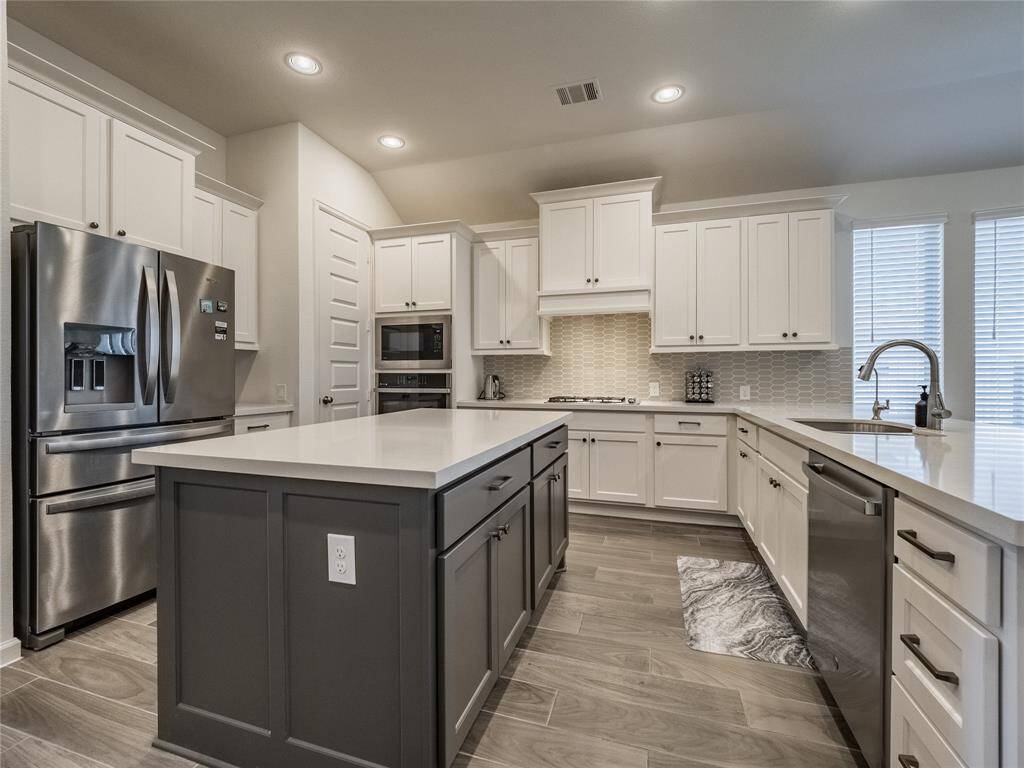 another view of the spacious kitchen with stainless steel appliances and refrigerator stays