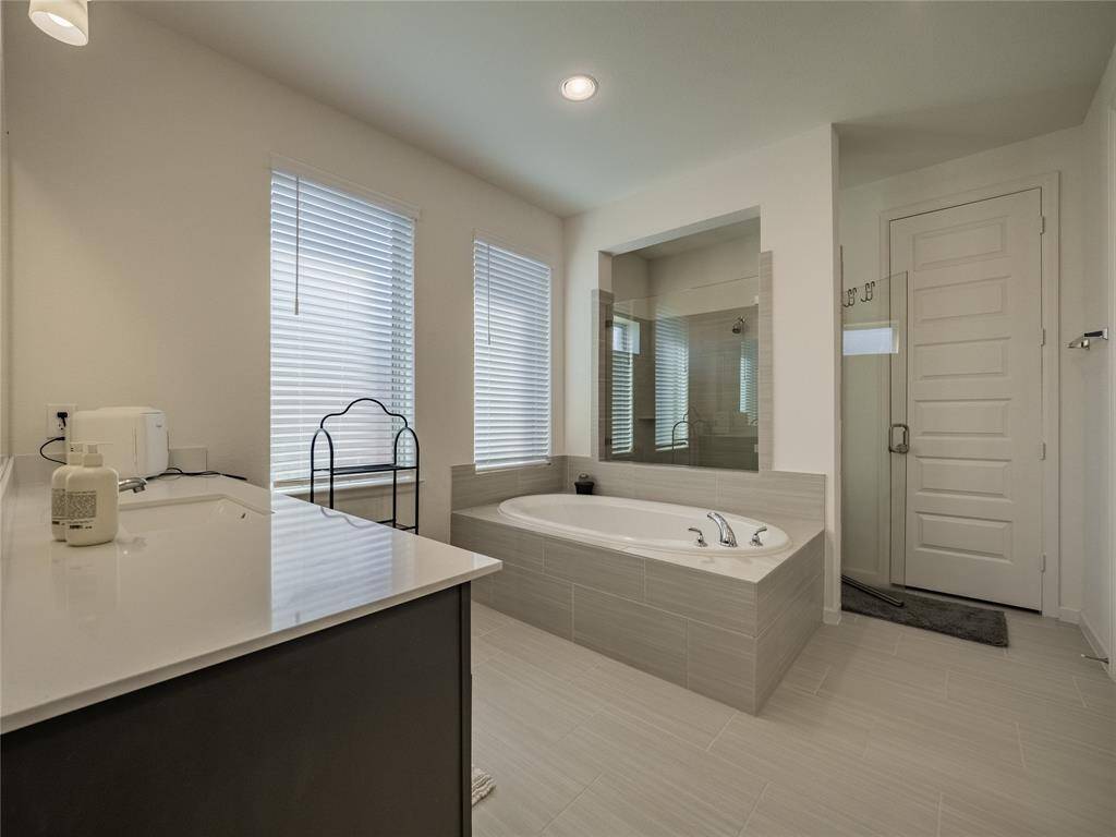 from this view you can see the glass walk in shower behind the tub and entrance to the walk in closet