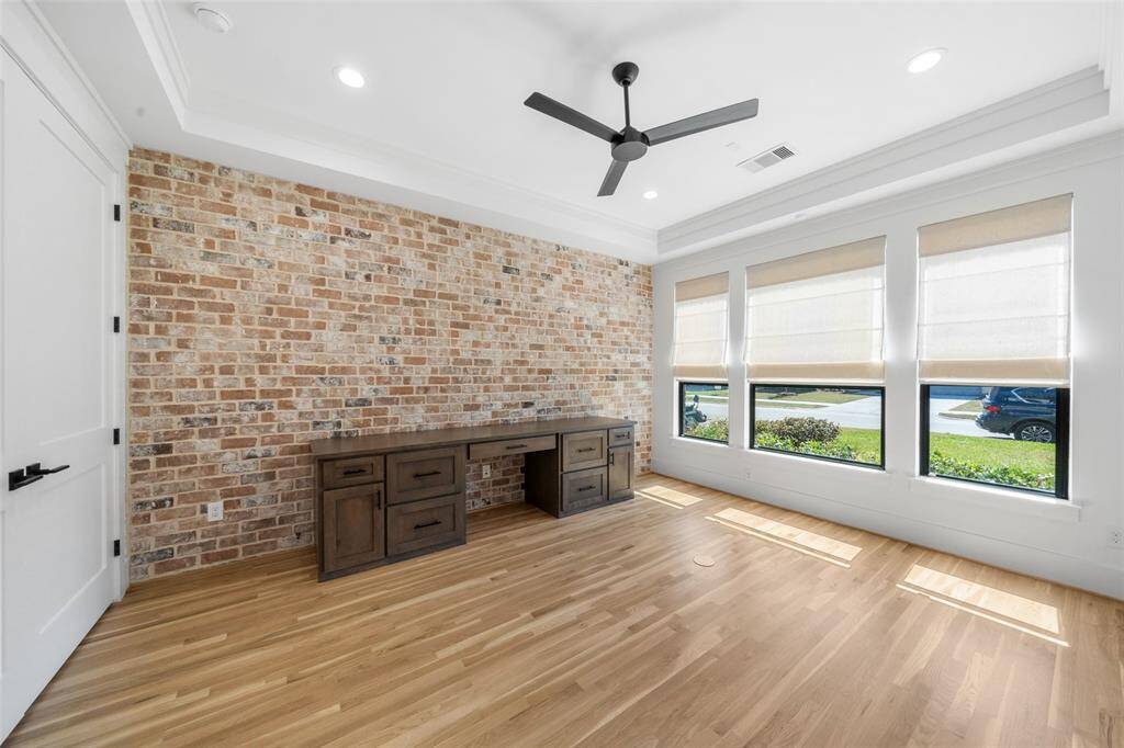 Office with brick accent wall and custom built-in desk.