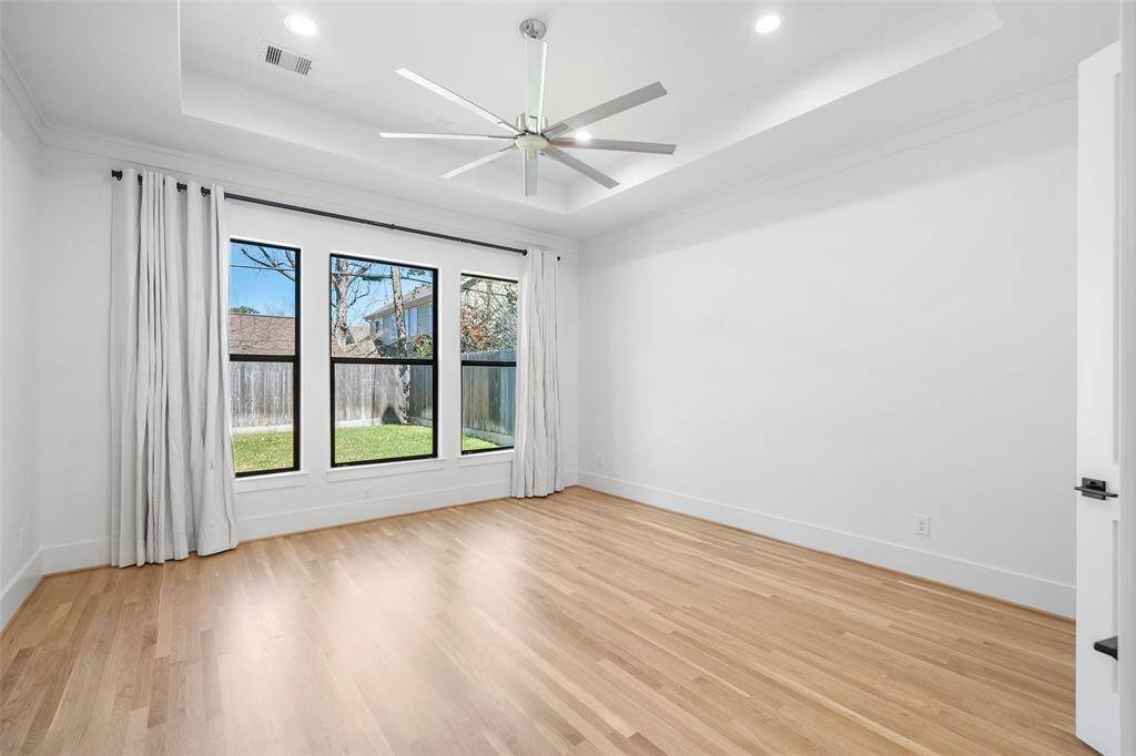 Primary bedroom features a raised ceiling and custom privacy curtains.