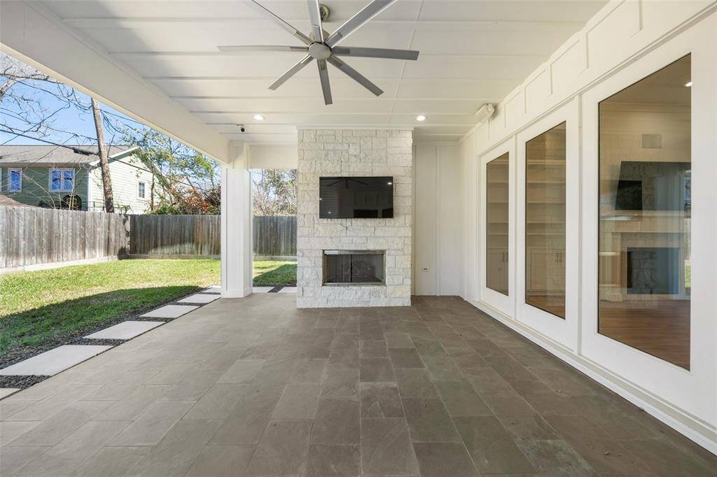 Off the living and dining room is a covered patio with gaslog fireplace, tv, amika fan, and surround sound.