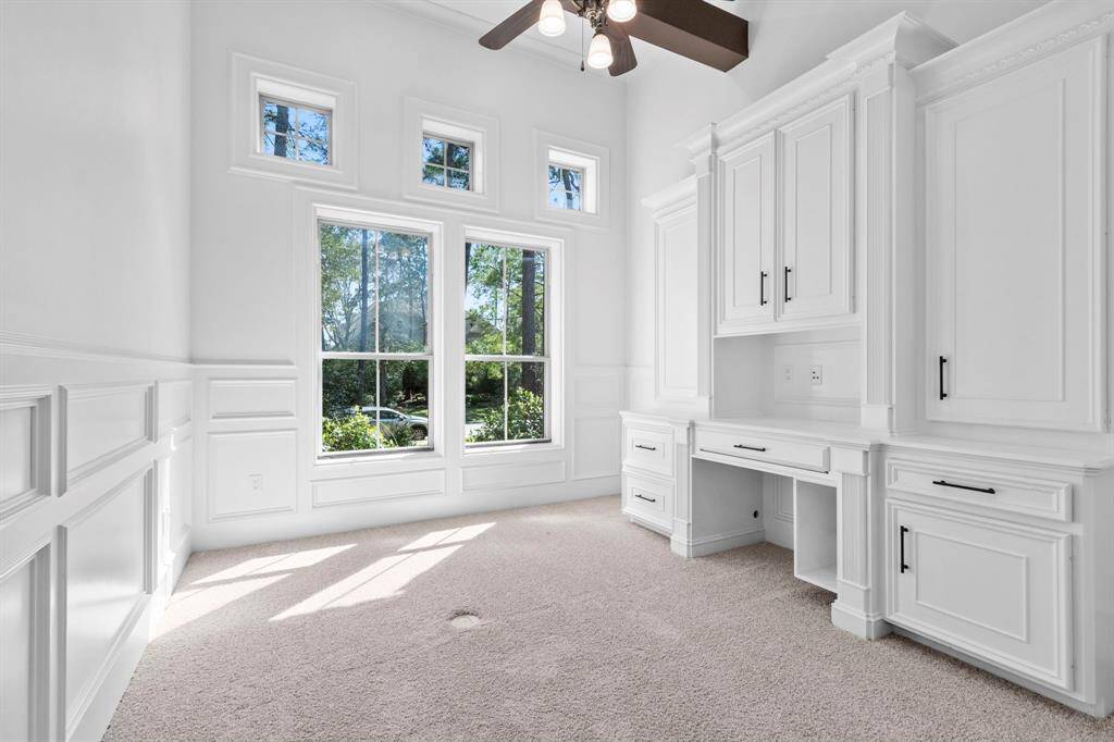Sophisticated mid-level study with a built-in desk, cabinetry, wainscoting, and a  stunning wood-beamed ceiling.